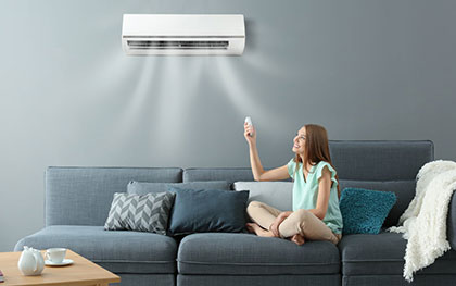 woman on a couch under a split air conditioner