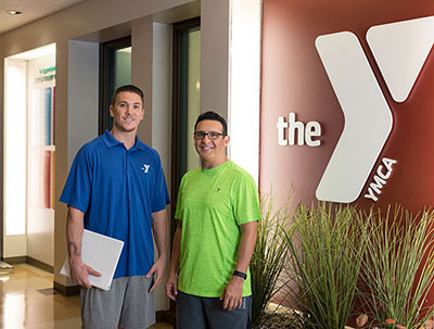 2 YMCA program directors standing next to logo