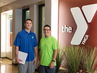 2 YMCA program directors standing next to logo